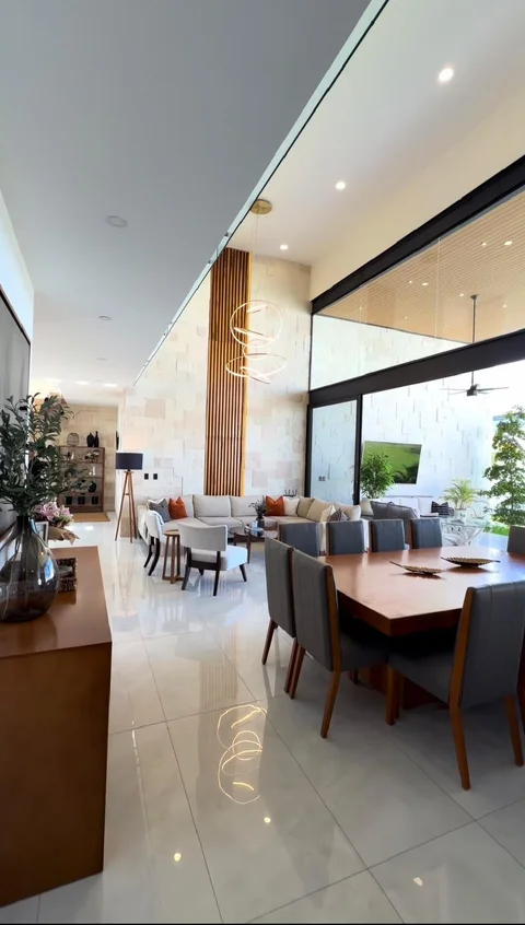 Sala y comedor a doble altura con muro de piedra, listones de madera y ventanales hacia la terraza