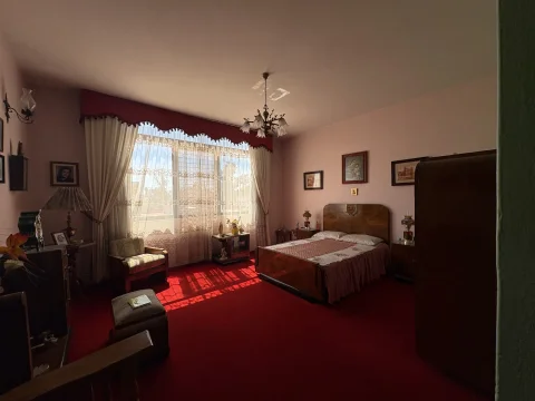 Recámara con ventanal, cortinas y alfombra roja