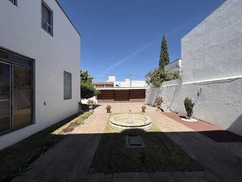 Patio con fuente y jardín junto a la construcción