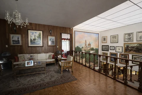 Sala con muros de madera, cuadros y barandal