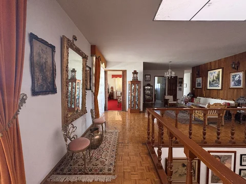 Vestíbulo con espejo y barandal de madera hacia la sala